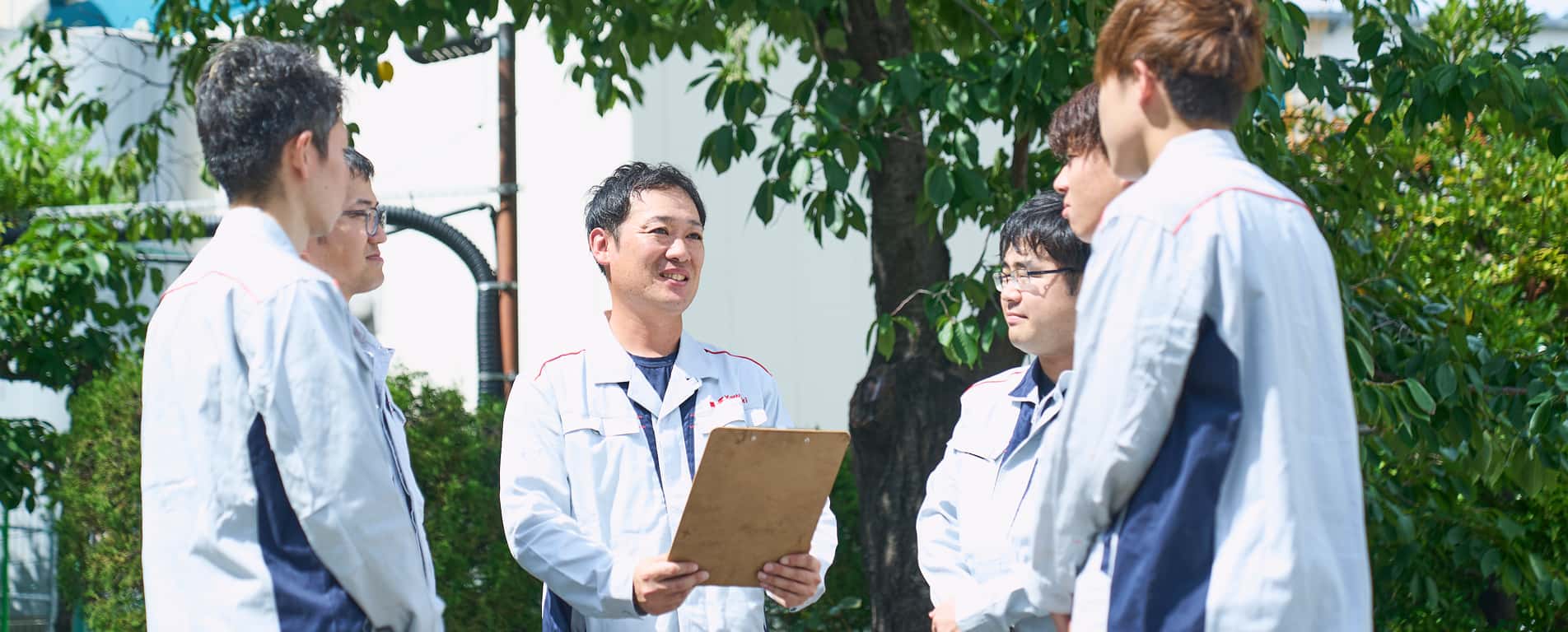 作業服姿の男性が集まってミーティングしている写真